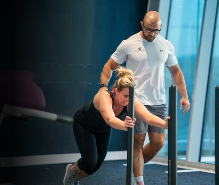 trainee pushing weight with trainer