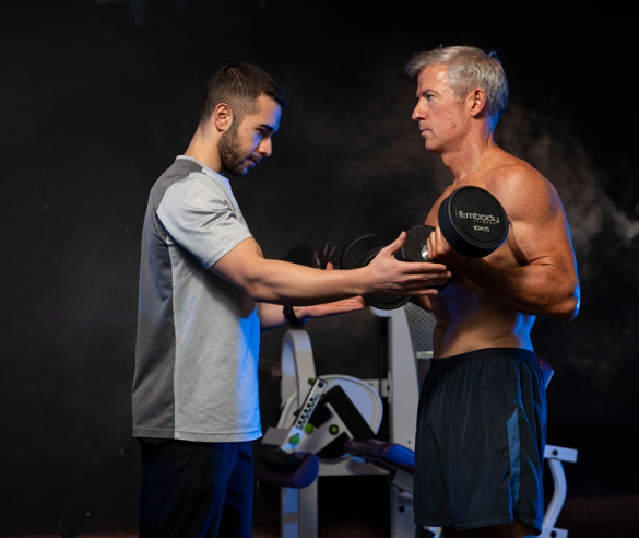 trainee doing bicep curls with trainer
