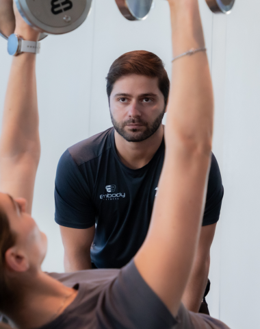 trainee doing dumbbell press with trainer