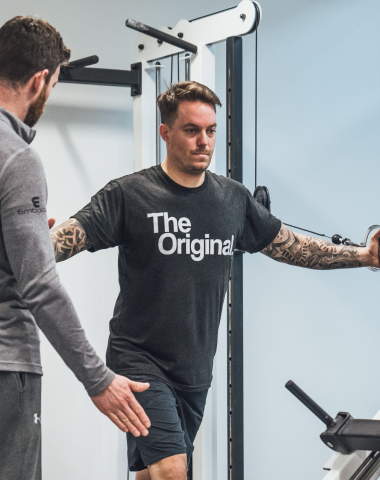 trainee doing pec flys with trainer