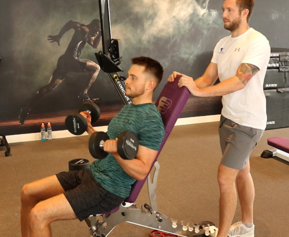 trainee doing bicep curls with trainer