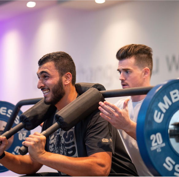 trainer spotting trainee doing squats