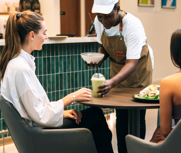barista handing drink to woman